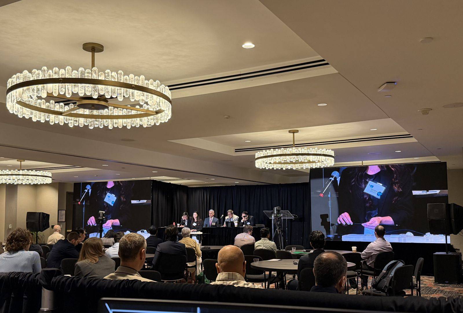 LED video walls showing a live close-up camera feed of a hands-on demonstration at a medical conference