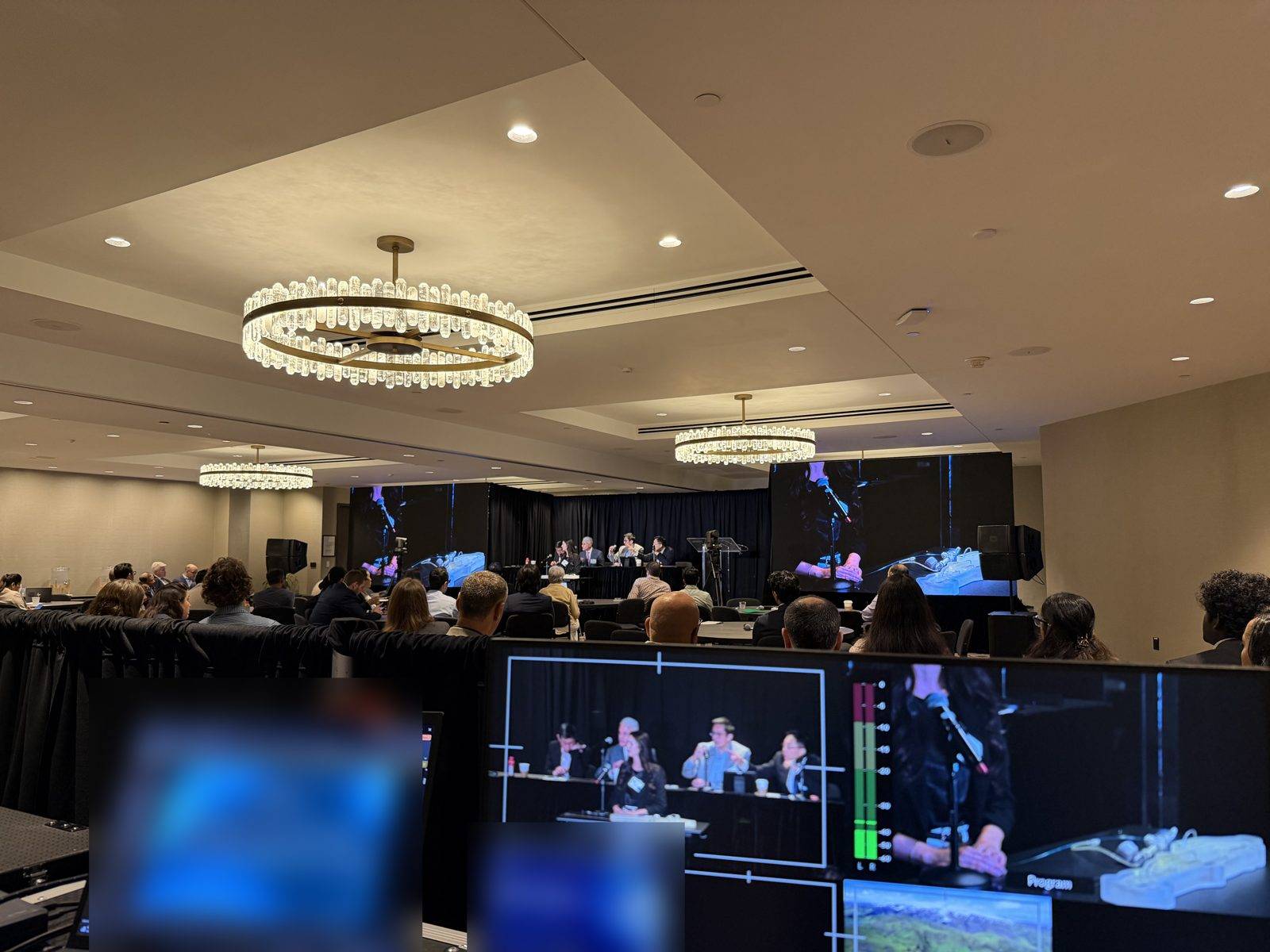 Preview and program monitors at the production table while LED walls show the live demo at a conference